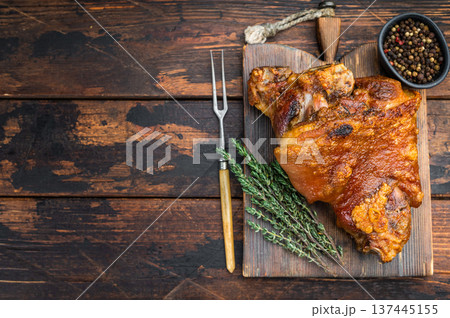 German style Schweinshaxe featuring seared caramelized skin, rendered fatcap, tender meat fibers and thyme on dark wooden surface. German style Schweinshaxe featuring seared caramelized skin, rendered fatcap, tender meat fibers and thyme on dark wooden surface. 137445155