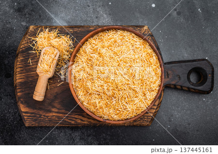 Kataifi shredded phyllo pastry dough in wooden bowl with scoop on rustic board. Traditional dessert ingredient flatlay 137445161
