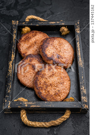 Vegan meatless burger patties plant based protein ready to eat presented in wooden tray on black background 137445162