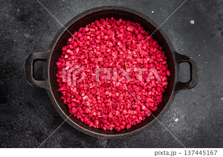 Sublimated raspberry granules with intense red color in cast iron pan. Natural ingredient flatlay with copy space 137445167