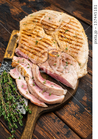 Grilled bone in pork shoulder sliced and whole on wooden board with knife and herbs on rustic table cooked meat with copy space Grilled bone in pork shoulder sliced and whole on wooden board with knife and herbs on rustic table cooked meat with copy space 137445181