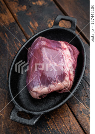 Raw heart used in pork cuisine placed on cast iron with thyme showing dense muscle fibers on rustic wood background. 137445186