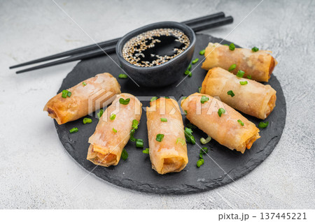 Crispy Egg rolls arranged on round slate plate with soy sauce and sesame seeds flat lay light background Crispy Egg rolls arranged on round slate plate with soy sauce and sesame seeds flat lay light background 137445221