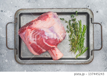 Raw beef shank with bone in metal tray with rosemary thyme and pink salt uncooked meat on light background for osso buco Raw beef shank with bone in metal tray with rosemary thyme and pink salt uncooked meat on light background for osso buco 137445243