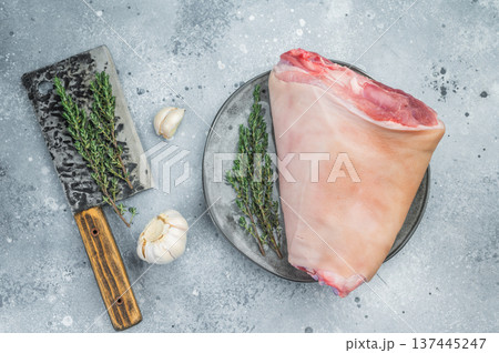 Uncooked pork shank hamhock with bone section, collagen fibers and skin layer arranged on plate with herbs ideal for butchery documentation. Uncooked pork shank hamhock with bone section, collagen fibers and skin layer arranged on plate with herbs ideal for butchery documentation. 137445247