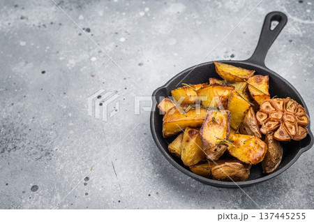 Baked potato wedges seasoned with rosemary and garlic in skillet. Simple healthy side dish with copy space 137445255