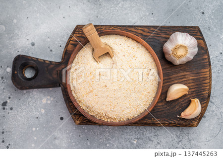 Dehydrated garlic granules with whole garlic and cloves. Aromatic spice ingredient flatlay on gray concrete background 137445263