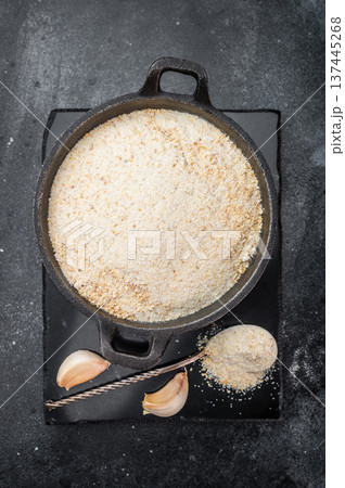 Dried granulated garlic seasoning with fine texture in skillet. Culinary ingredient flatlay on dark background Dried granulated garlic seasoning with fine texture in skillet. Culinary ingredient flatlay on dark background 137445268