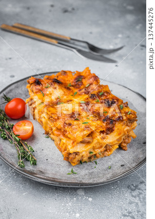 Homemade beef lasagna portion with baked cheese thyme garnish and cherry tomatoes on light stone background 137445276