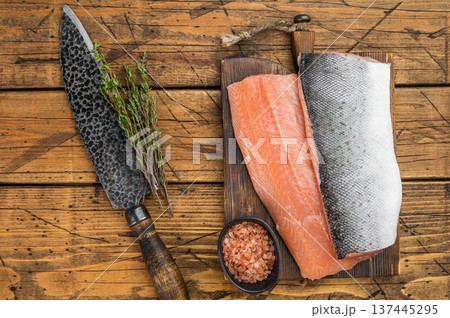 Raw Atlantic salmon fillet skin on and skinless on wooden board with knife and herbs. Fresh seafood on rustic wooden background with copy space. Raw Atlantic salmon fillet skin on and skinless on wooden board with knife and herbs. Fresh seafood on rustic wooden background with copy space. 137445295