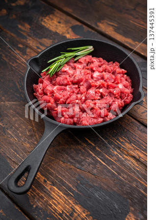 Raw chopped beef veal meat with herbs in black skillet over bright surface perfect for recipe design culinary ads and protein rich visuals. Raw chopped beef veal meat with herbs in black skillet over bright surface perfect for recipe design culinary ads and protein rich visuals. 137445391