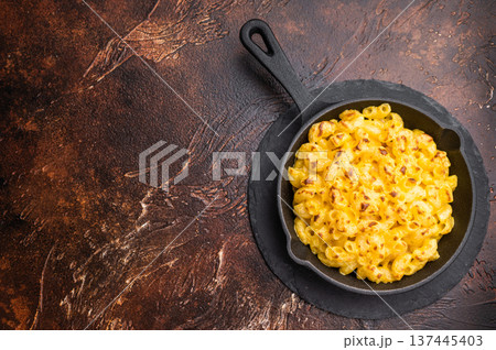 Baked mac and cheese in a black skillet, set against a rustic dark brown background Baked mac and cheese in a black skillet, set against a rustic dark brown background 137445403