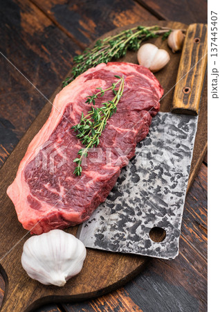 Fresh New York strip steak with thyme and metal cleaver on textured wooden board ideal for barbecue recipe and grill menu designs. Fresh New York strip steak with thyme and metal cleaver on textured wooden board ideal for barbecue recipe and grill menu designs. 137445407