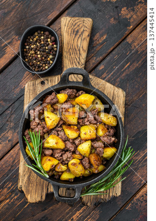Rustic beef hash with fried potatoes served in a cast iron skillet on a wooden board perfect for comfort food and recipe visuals. Rustic beef hash with fried potatoes served in a cast iron skillet on a wooden board perfect for comfort food and recipe visuals. 137445414