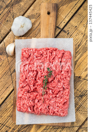 Uncooked minced veal and mutton meat slab with herbs, garlic and salt on wooden board highlighting raw texture for culinary and food prep visuals. Uncooked minced veal and mutton meat slab with herbs, garlic and salt on wooden board highlighting raw texture for culinary and food prep visuals. 137445425