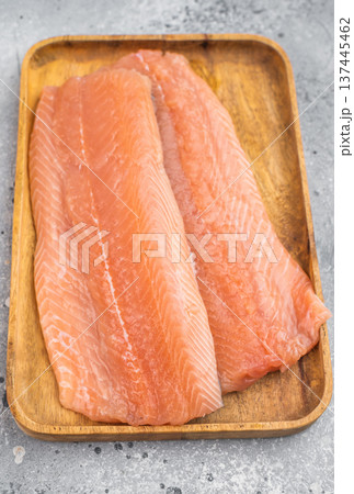 Fresh raw salmon fillet Salmo salar on wooden board. Clean flat lay food photography with salt on light gray background.. Fresh raw salmon fillet Salmo salar on wooden board. Clean flat lay food photography with salt on light gray background.. 137445462