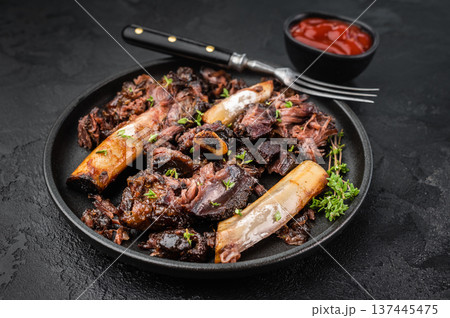 Cooked beef ribs slow cooked until tender with pulled meat and bones. BBQ style beef plate ribs on dark background with copy space. Cooked beef ribs slow cooked until tender with pulled meat and bones. BBQ style beef plate ribs on dark background with copy space. 137445475
