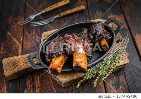 Cooked beef plate ribs slow cooked until tender with bone and herbs. BBQ style beef plate ribs on dark wooden background with copy space. Cooked beef plate ribs slow cooked until tender with bone and herbs. BBQ style beef plate ribs on dark wooden background with copy space. 137445480