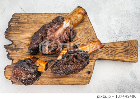 Slow cooked beef short ribs with bone on wooden board and BBQ sauce. Tender braised beef ribs plate style on light background. Slow cooked beef short ribs with bone on wooden board and BBQ sauce. Tender braised beef ribs plate style on light background. 137445486