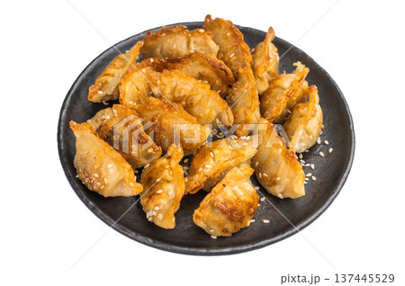 Crispy pan fried jiaozi dumplings with sesame served on dark plate. Asian mandu potstickers photographed top view on light background. Crispy pan fried jiaozi dumplings with sesame served on dark plate. Asian mandu potstickers photographed top view on light background. 137445529
