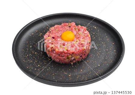 Beef tartare with egg yolk on a black plate over bright background perfect for gourmet recipes restaurant menus and premium food stock images. Beef tartare with egg yolk on a black plate over bright background perfect for gourmet recipes restaurant menus and premium food stock images. 137445530