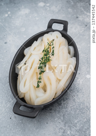 Fresh calamari rings in cast iron bowl with thyme on textured gray background ideal seafood ingredient for gourmet cooking. 137445542