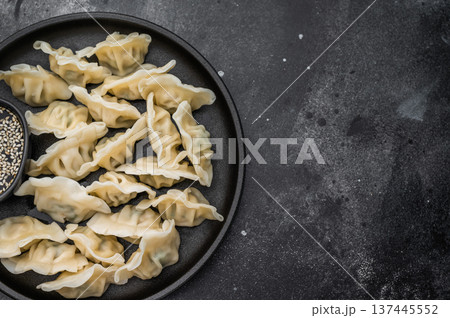 Fresh asian dumplings mandu served on a dark textured surface. Minimal food composition ideal for restaurant ads and stock use. 137445552