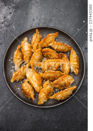 Crunchy gyoza wonton dumplings on dark stone background savory Asian dish with golden crust and sesame garnish 137445560