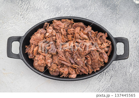 Tender slow cooked venison and elk stew with herbs in a cast iron dish on a light textured background for rustic gourmet food concepts. Tender slow cooked venison and elk stew with herbs in a cast iron dish on a light textured background for rustic gourmet food concepts. 137445565