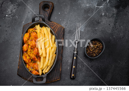 German currywurst with fries in a cast iron pan on dark background perfect for street food visuals fast food ads and stock images. 137445566