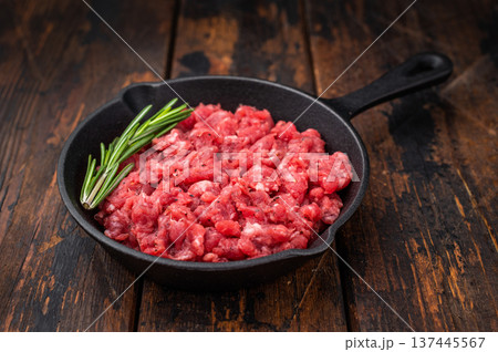 Raw chopped beef veal meat with herbs in black skillet over bright surface perfect for recipe design culinary ads and protein rich visuals. 137445567