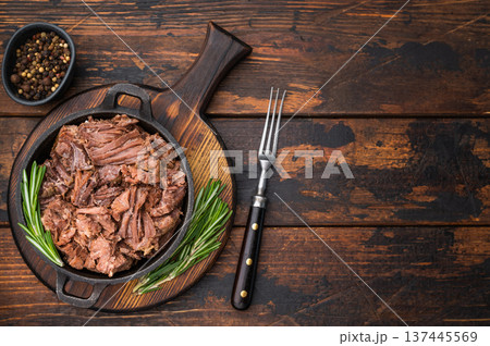 Shredded moose meat braised to perfection in castiron skillet with herbs and pepper on dark wooden board creating rich rustic wild game dish Shredded moose meat braised to perfection in castiron skillet with herbs and pepper on dark wooden board creating rich rustic wild game dish 137445569