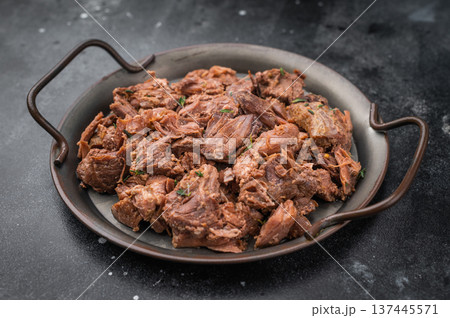 Rustic braised moose venison stew, shredded and savory, plated with fresh rosemary on a metal dish over dark stone background Rustic braised moose venison stew, shredded and savory, plated with fresh rosemary on a metal dish over dark stone background 137445571