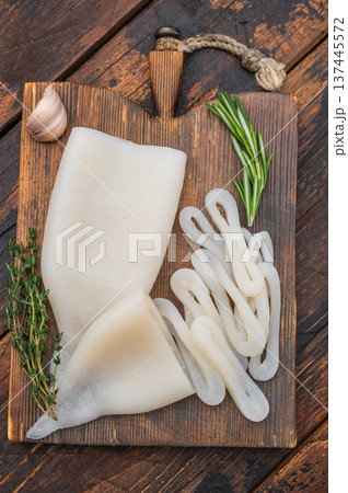 White fresh calamari ring displayed on rustic board with herbs ideal for seafood recipes menus and professional food photography. 137445572