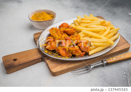 German currywurst with crispy fries on metal plate over wooden board and concrete background ideal for street food ads and stock images. 137445583