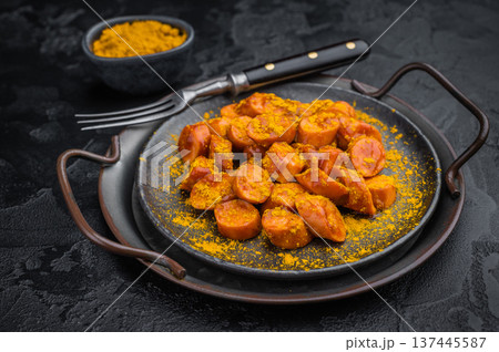 German currywurst, sausages with curry spice served on rustic metal plate over dark textured background perfect for street food and stock imagery. German currywurst, sausages with curry spice served on rustic metal plate over dark textured background perfect for street food and stock imagery. 137445587
