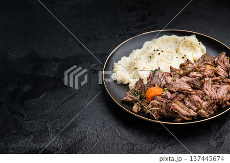 Beef stew with mashed potatoes, carrots and herbs on a plate isolated. black background. top view Beef stew with mashed potatoes, carrots and herbs on a plate isolated. black background. top view 137445674