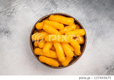 Irresistible Cheese puffs, cheese snacks bursting with bold flavors and a satisfying crunch. grey background. top view Irresistible Cheese puffs, cheese snacks bursting with bold flavors and a satisfying crunch. grey background. top view 137445675