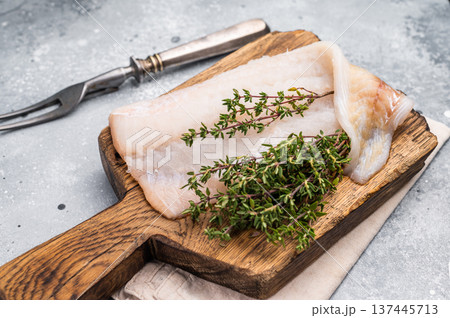 Fresh cod fish fillet, showcasing its delicate texture and pristine color, perfect for grilling or baking. grey background. top view Fresh cod fish fillet, showcasing its delicate texture and pristine color, perfect for grilling or baking. grey background. top view 137445713
