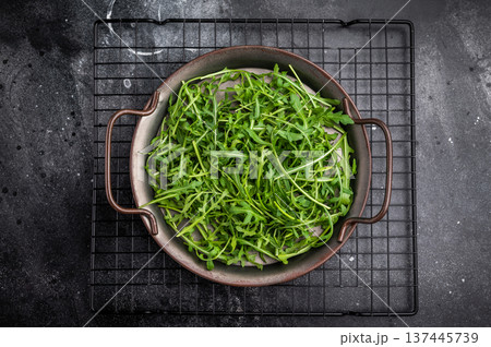 Lush rocket greens, showcasing their unique shape and rich color. A delightful addition to any dish. black background. top view 137445739