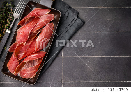 Dry cured and smoked serrano ham, pork meat. black background. top view Dry cured and smoked serrano ham, pork meat. black background. top view 137445749