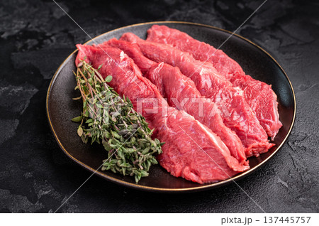 Raw sliced horse meat steaks presented with herbs and spices, inviting creativity in the kitchen for those seeking bold flavors and unique dining experiences. black background. top view 137445757