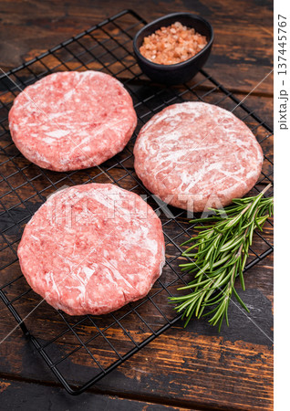 Frozen Meat patties ready for grilling, forcemeat of pork and beef for burgers. wooden background. top view Frozen Meat patties ready for grilling, forcemeat of pork and beef for burgers. wooden background. top view 137445767