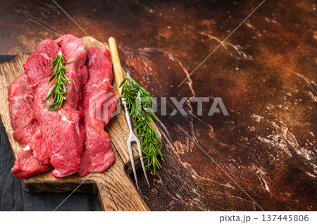 Beautifully arranged raw horse meat slices on a wooden platter, showcasing its appealing color and texture, perfect for cooking inspiration. brown background. top view 137445806