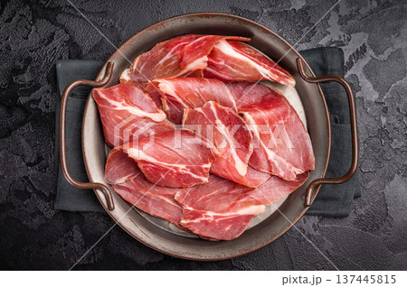 Thin slices of Speck, Jambon Italian cured meat. black background. top view Thin slices of Speck, Jambon Italian cured meat. black background. top view 137445815