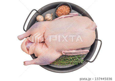 Uncooked duck carcass arranged with herbs and salt in rustic round tray against clean surface perfect for culinary food photography. 137445836
