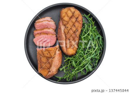 Gourmet roasted duck breast arranged with greens on dark plate against clean grey surface great for cooking blogs and stock photography. 137445844
