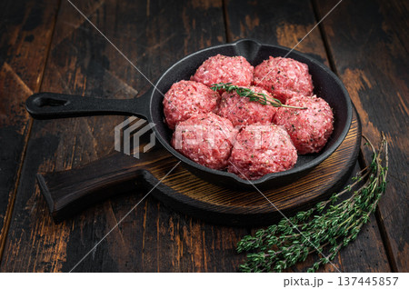 Groundmeat meatballs or Frikadel in cast iron pan on wooden board offering detailed texture ideal for grocery, cooking and nutrition imagery. 137445857