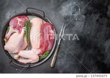 Fresh uncooked duck assortment arranged with thyme rosemary and garlic in rustic pan against textured dark surface perfect for culinary visuals. Fresh uncooked duck assortment arranged with thyme rosemary and garlic in rustic pan against textured dark surface perfect for culinary visuals. 137445875