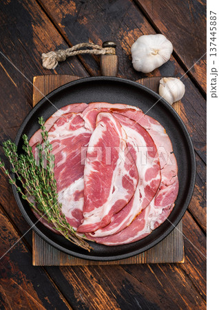 Spanish lomo slices with rosemary on a dark plate served on a wooden dark background for food stock. 137445887